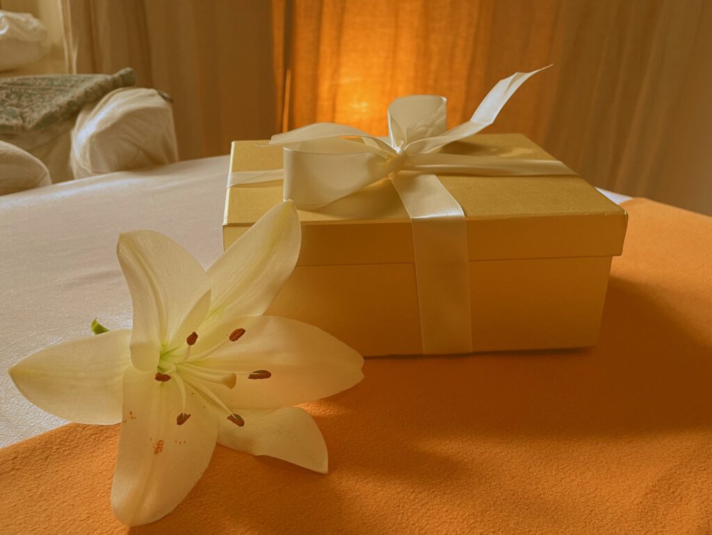 Gutschein-Geschenkbox mit Lilie auf der Massageliege